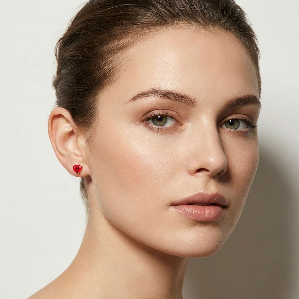Model wearing gold-plated studs with a bright red heart cubic zirconia