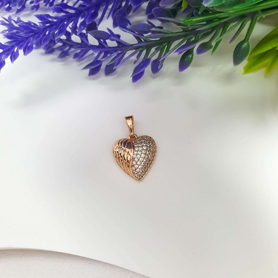 Side view of the winged heart pendant, showing its curve and densely set stones