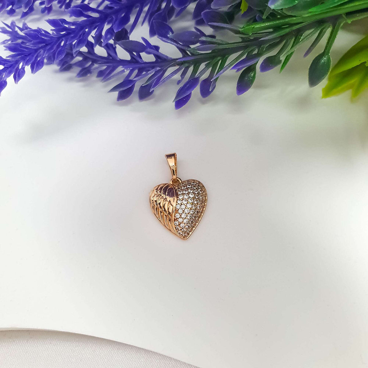 Side view of the winged heart pendant, showing its curve and densely set stones
