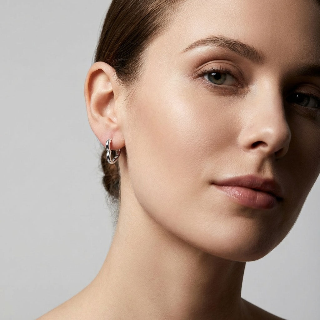 Close-up of a smooth silver-tone heart hoop on a model's ear