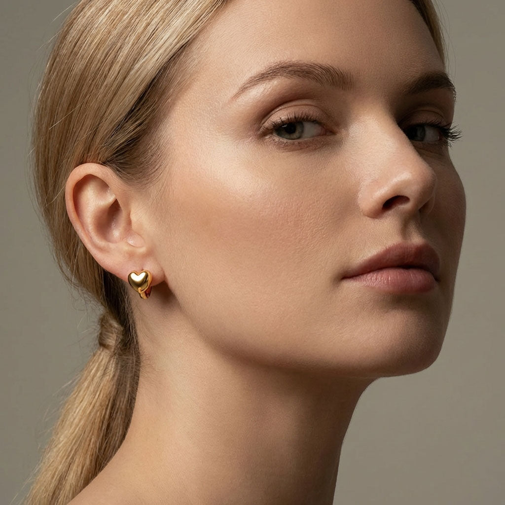 Gold-tone heart hoop worn in a model's ear