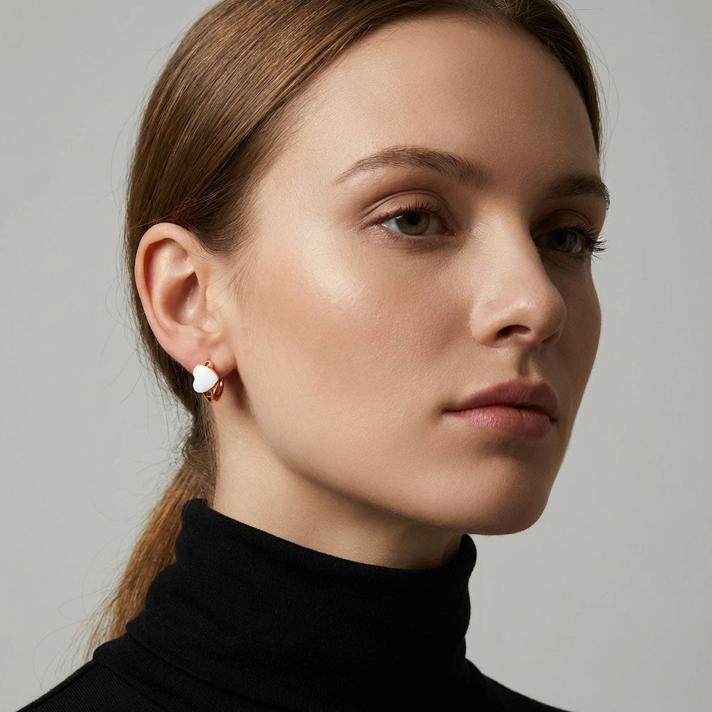 Model in a black polo neck wearing a gold-tone hoop with a white heart