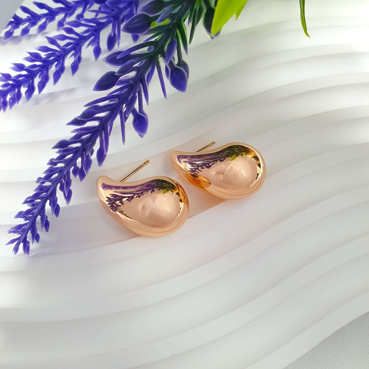 Pair of mirror-shine gold-plated teardrop studs beside lavender sprigs