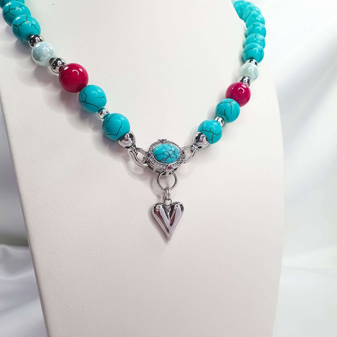 Close-up of turquoise necklace with pink beads and shiny silver-tone heart