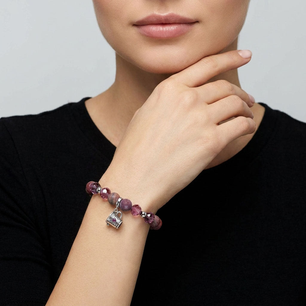 Woman wearing a matte agate bracelet with coffee cup charm against a black top