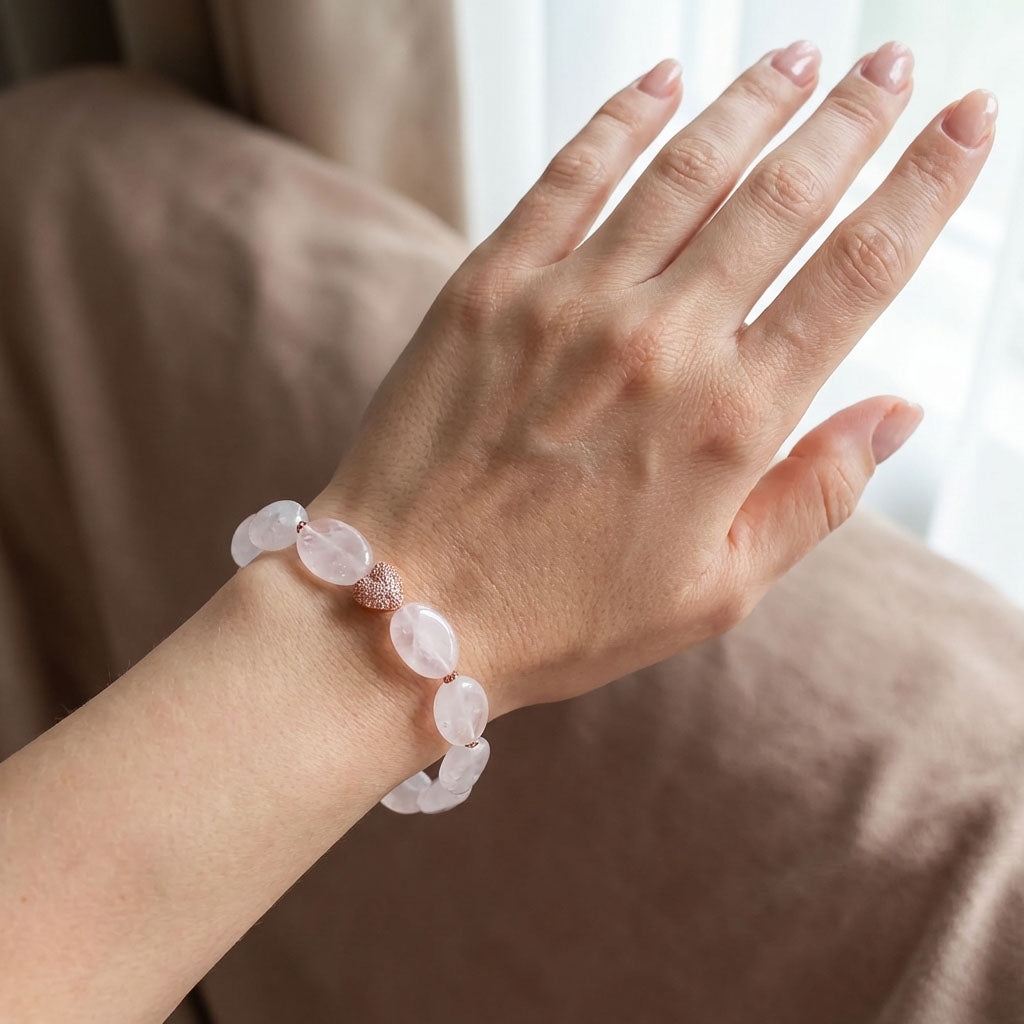 Pale quartz bracelet on a woman's wrist with sparkling rose gold-tone heart