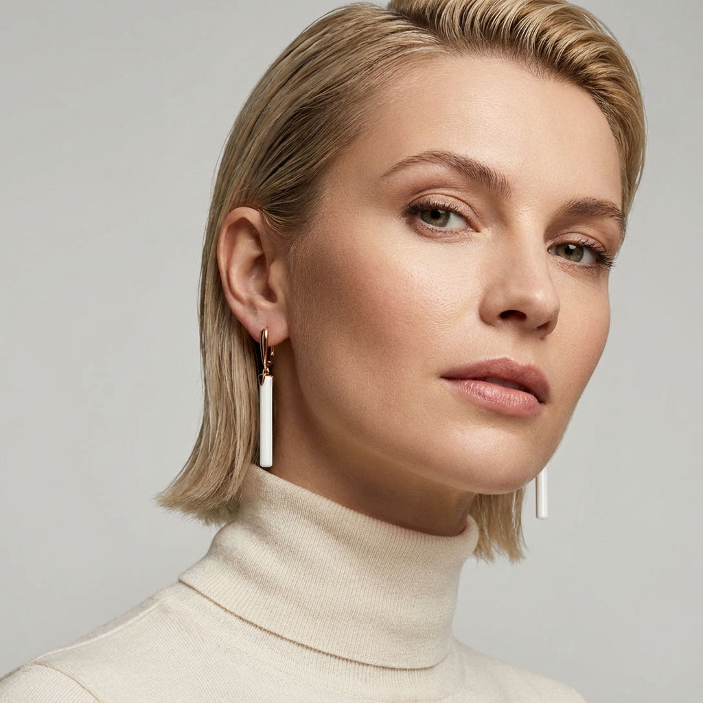 Blonde woman in a cream polo neck wearing long white ceramic earrings