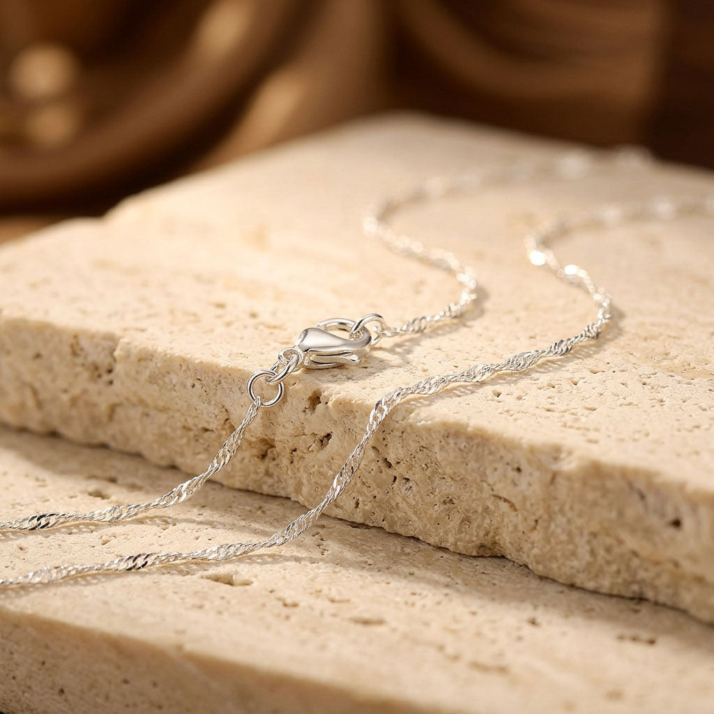 Fine Singapore chain with platinum plating and lobster clasp on a light stone slab