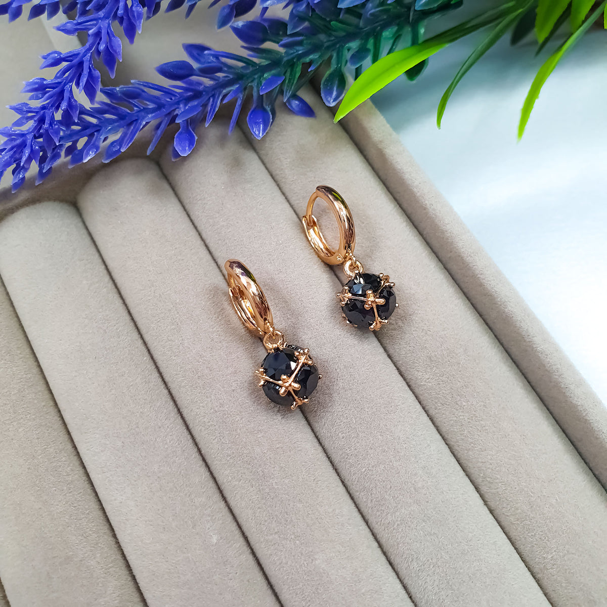 Black cubic zirconia earrings on a beige jewellery stand with flowers