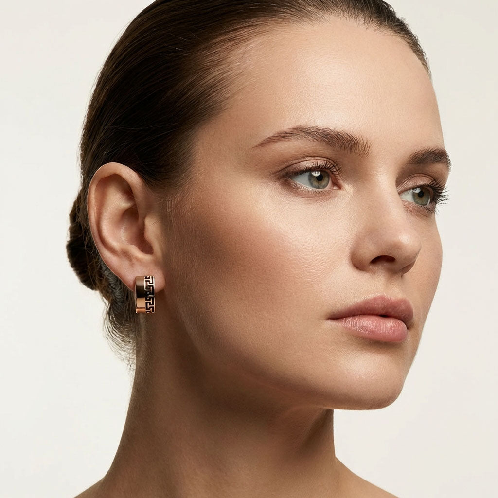 Meander pattern earring on a model's ear, warm golden tone with black enamel outline