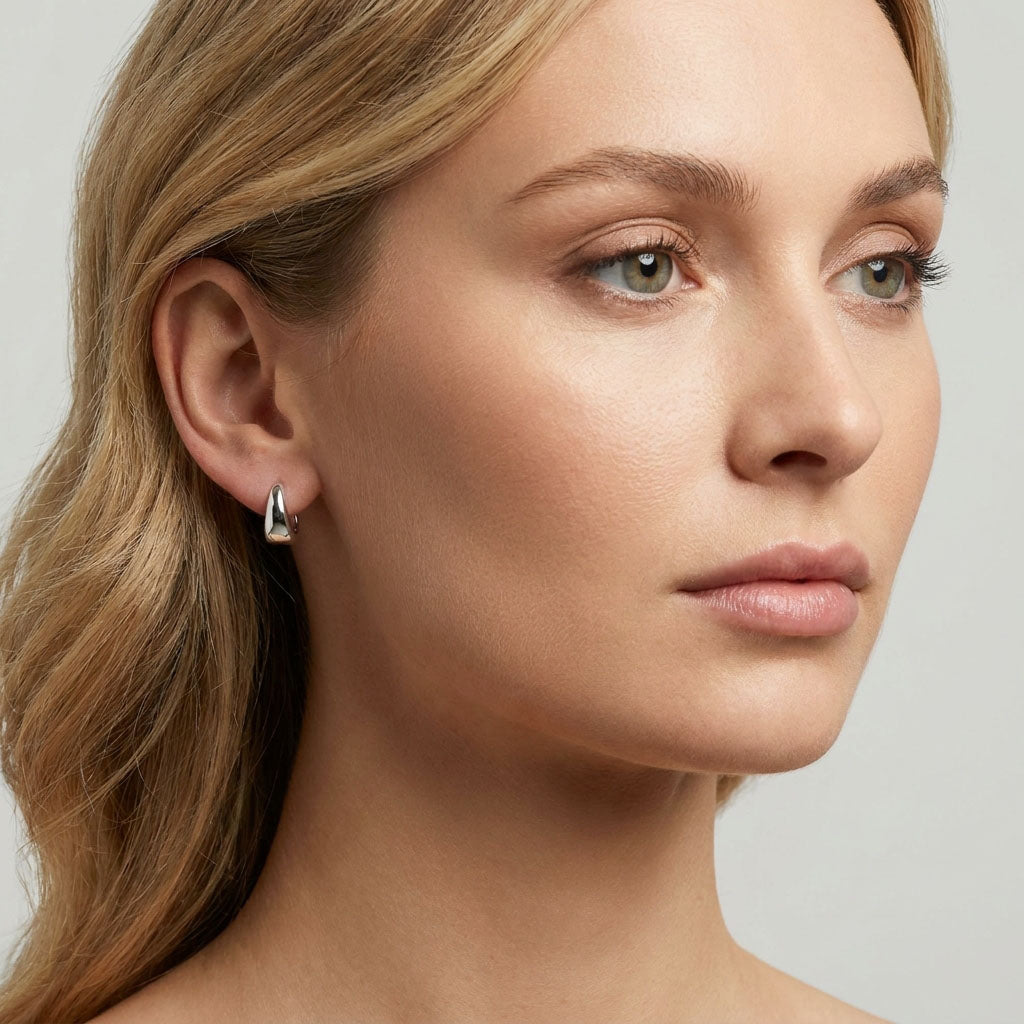 Smooth silver-tone hoop earring in a woman's ear, compact and stone-free