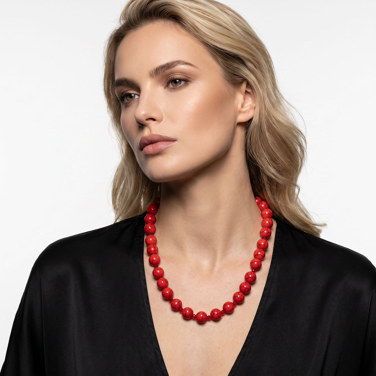 Woman in a black blouse wearing a red bead necklace with glass crystals