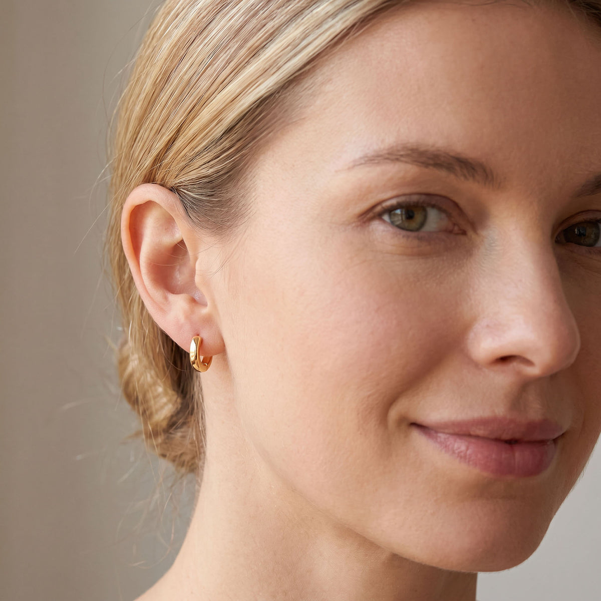 10x2 mm | Smooth gold-coloured hoop earring on a woman's ear