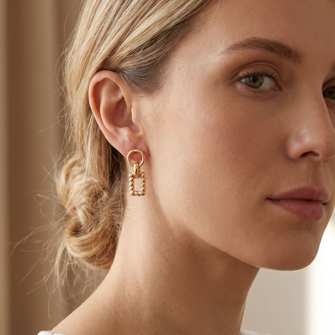 Gold | Gold-tone twisted rectangle earring worn on the ear