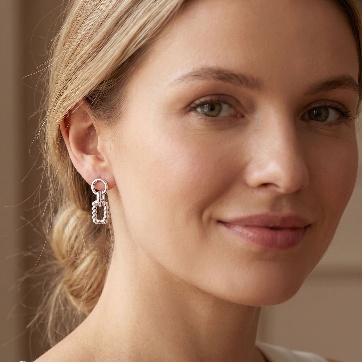 Silver | Silver-tone ring and twisted rectangle earring worn on the ear