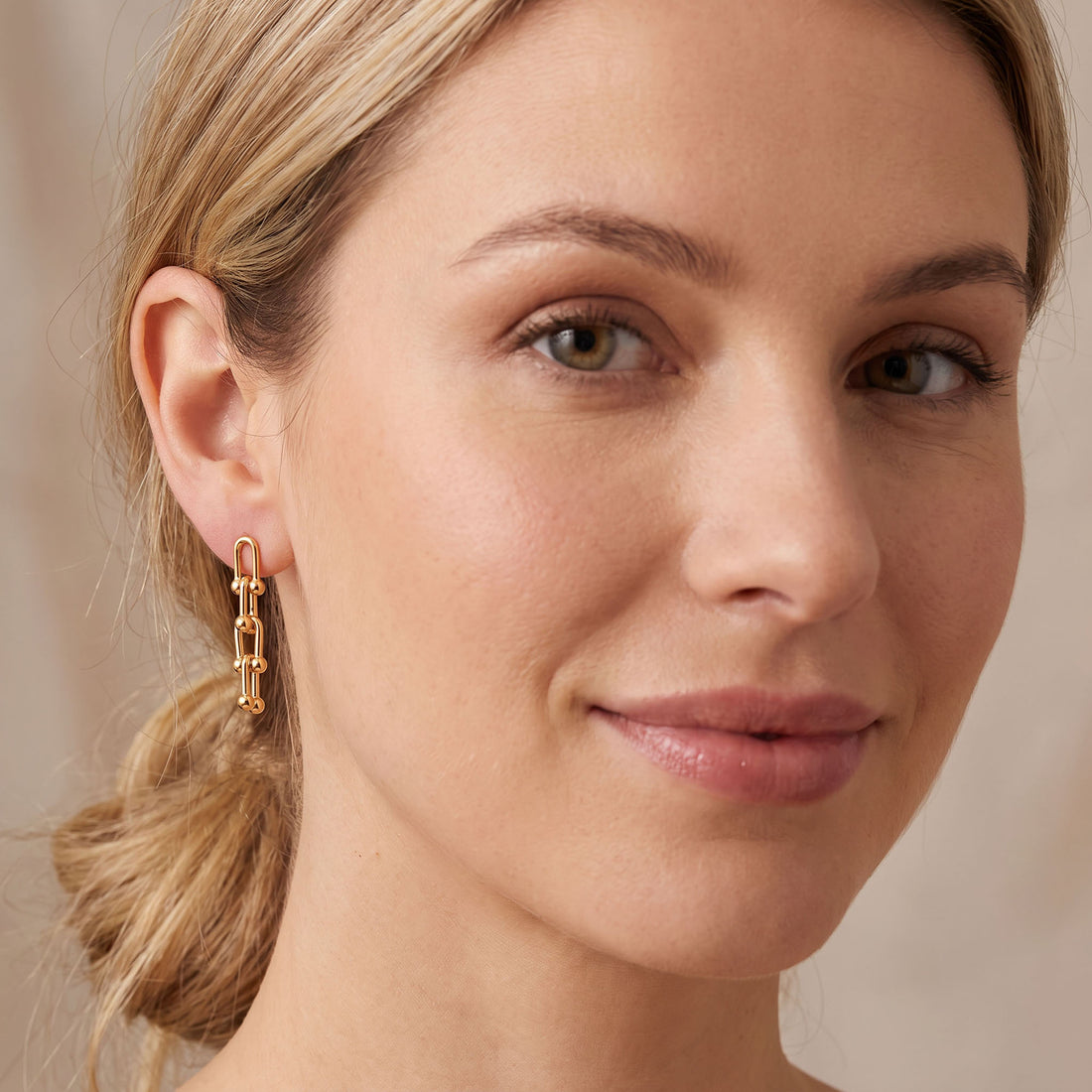 Gold-tone U-link dangle earring worn on the ear