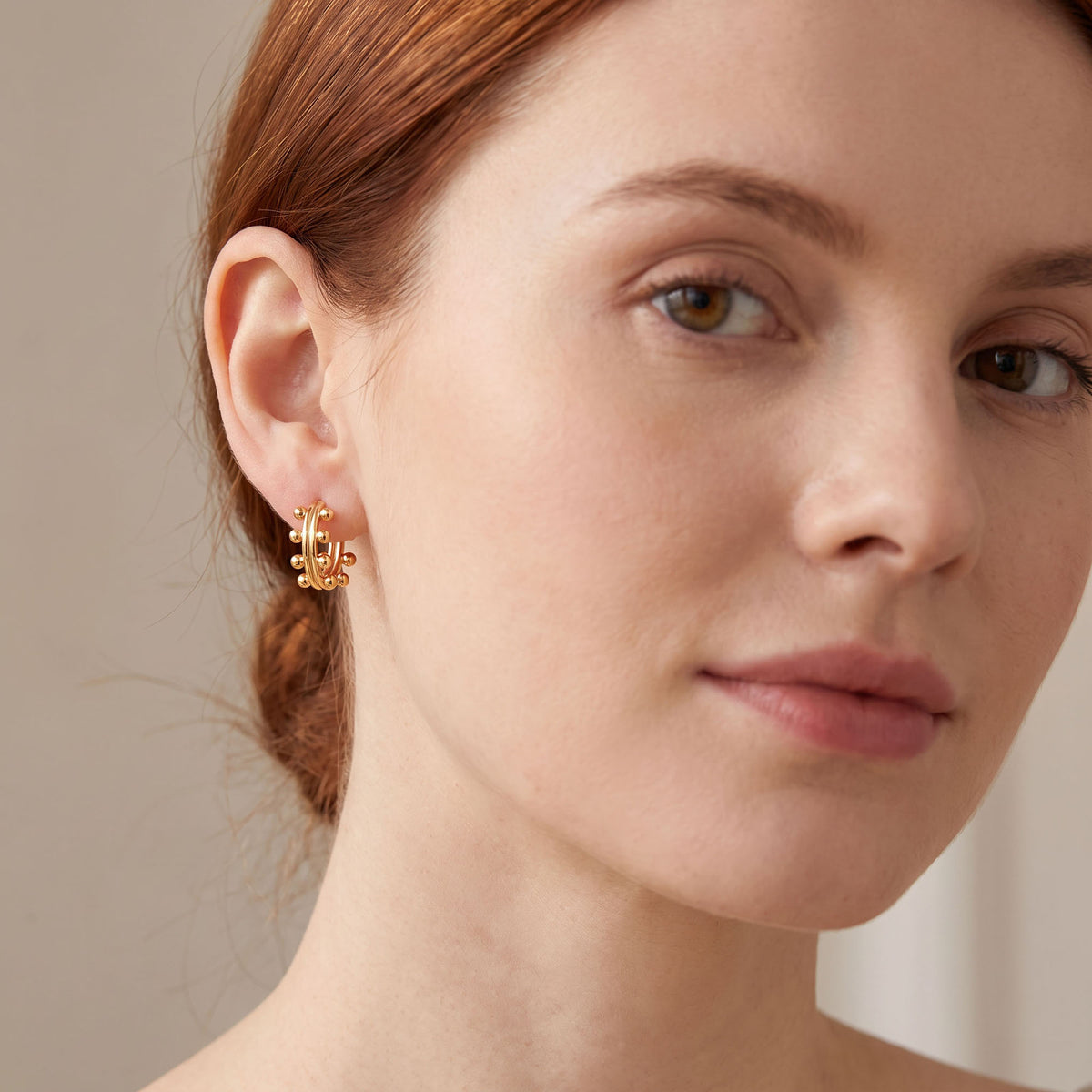Gold-tone ball-studded hoop worn on the ear