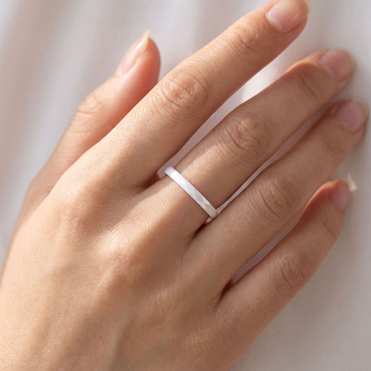 White | White faceted ceramic ring worn on a finger
