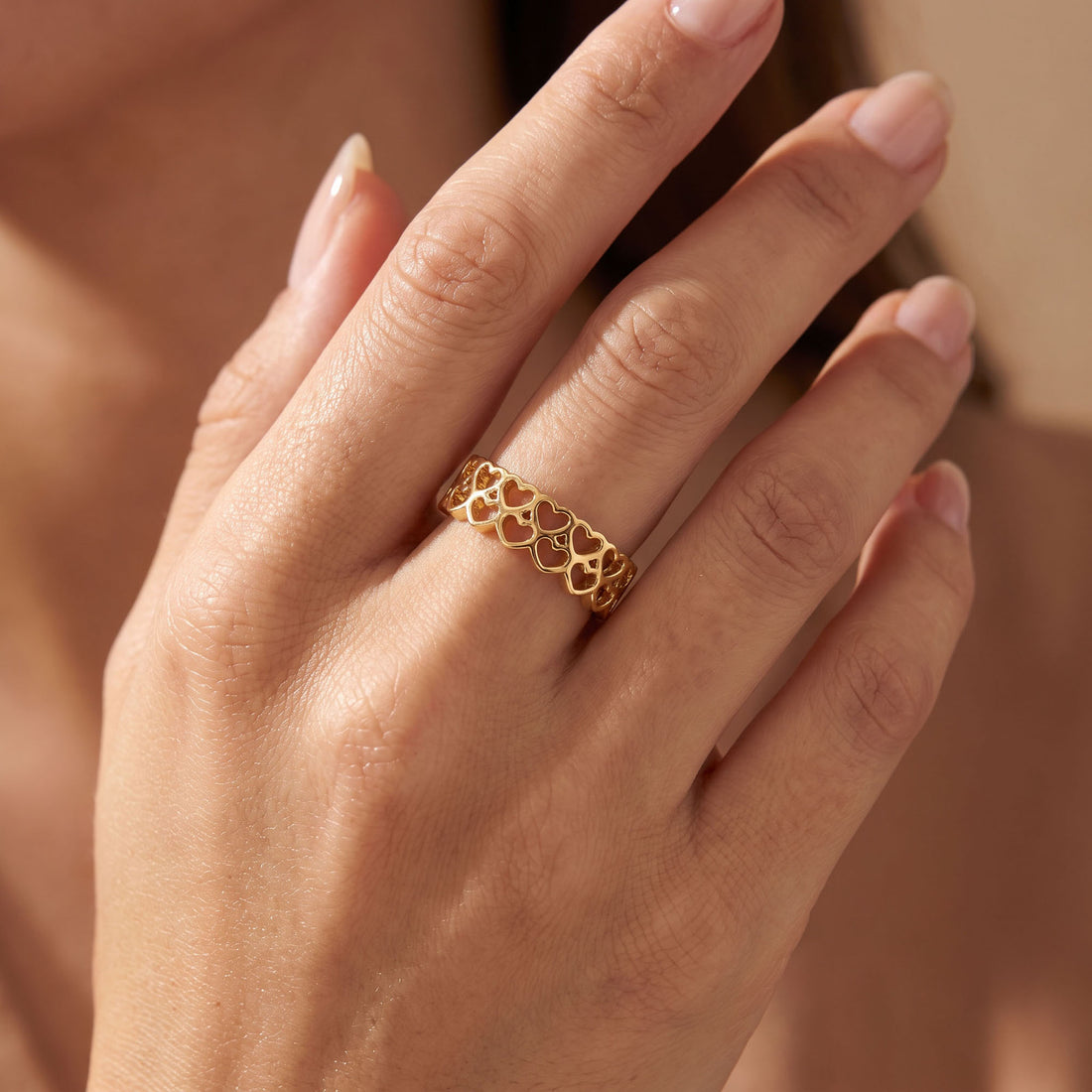 Gold-tone openwork heart ring worn on a woman's finger