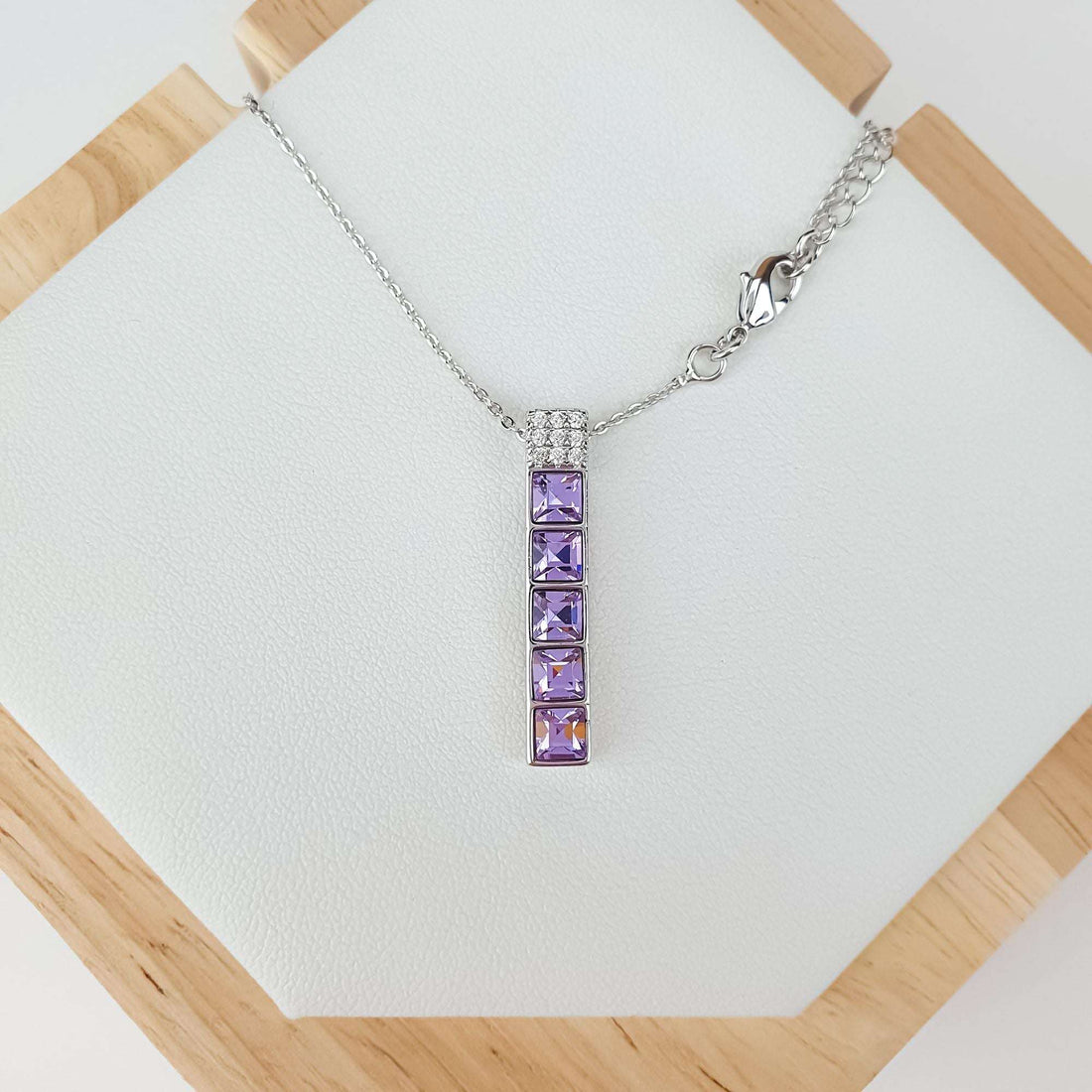 Necklace with a five-stone violet pendant in platinum tone on a white stand