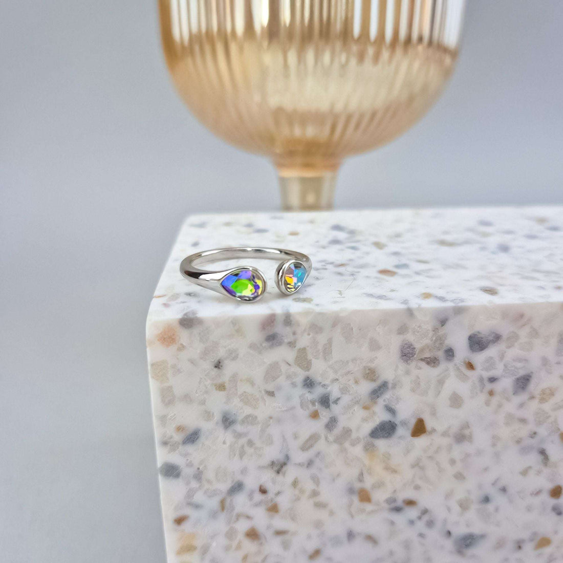 Adjustable platinum-plated ring on a terrazzo block beside a gold-coloured vase