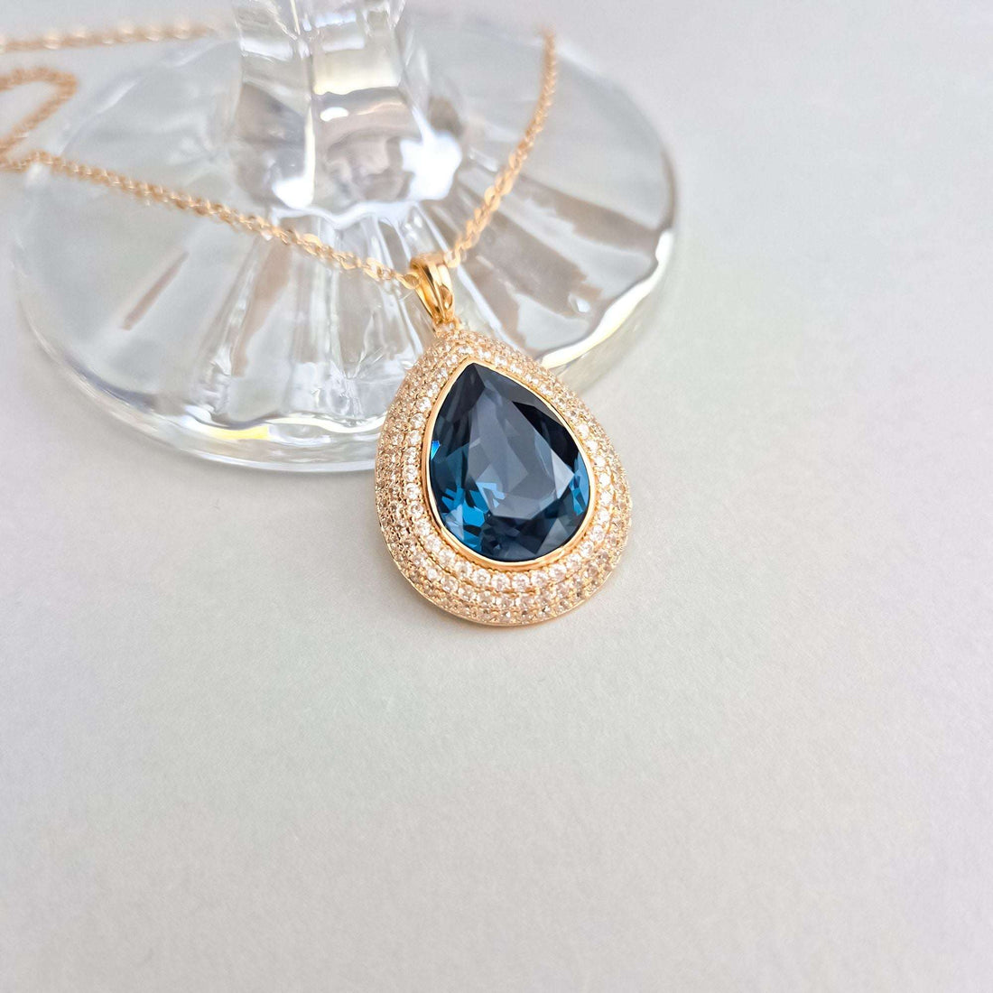 Close-up of the blue crystal pendant, its cubic zirconia rims glinting rose-gold