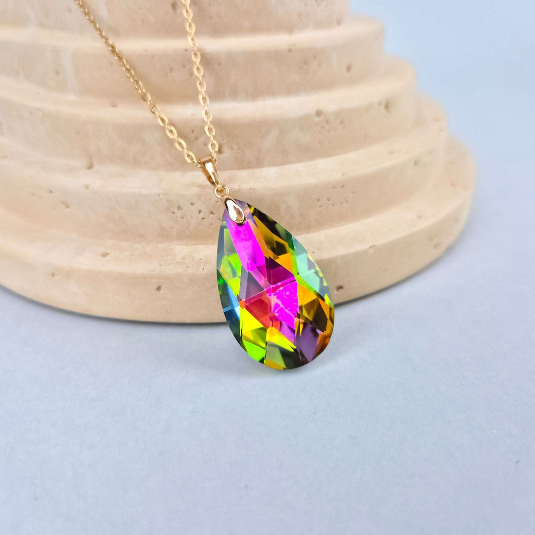 Close-up of the multicoloured crystal pendant on stone, showing the play of colour