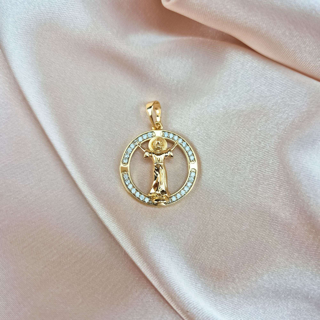 Gold-plated angel pendant in a round frame of white stones on soft pink silk
