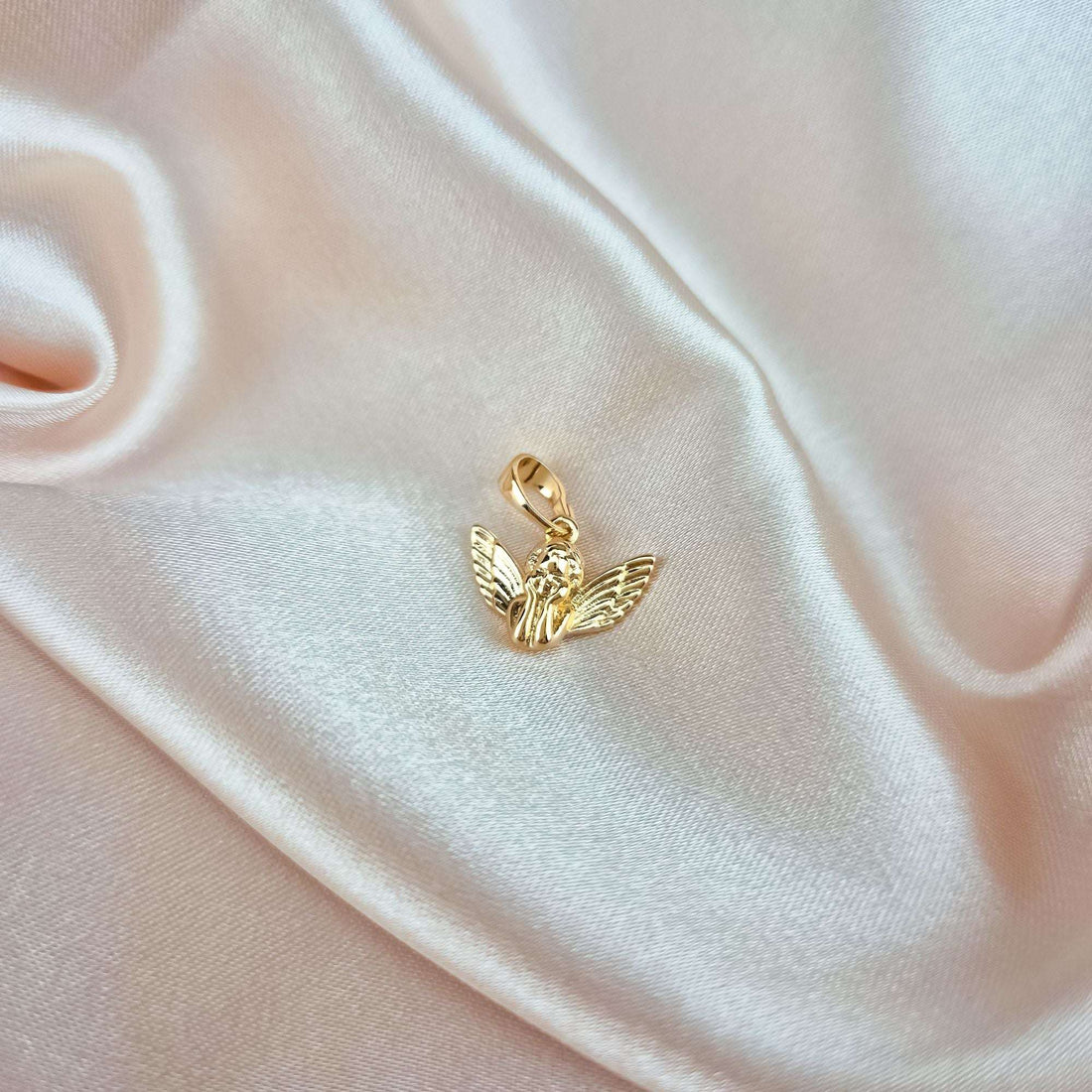 Small gold-plated angel pendant on cream silk showing its true size