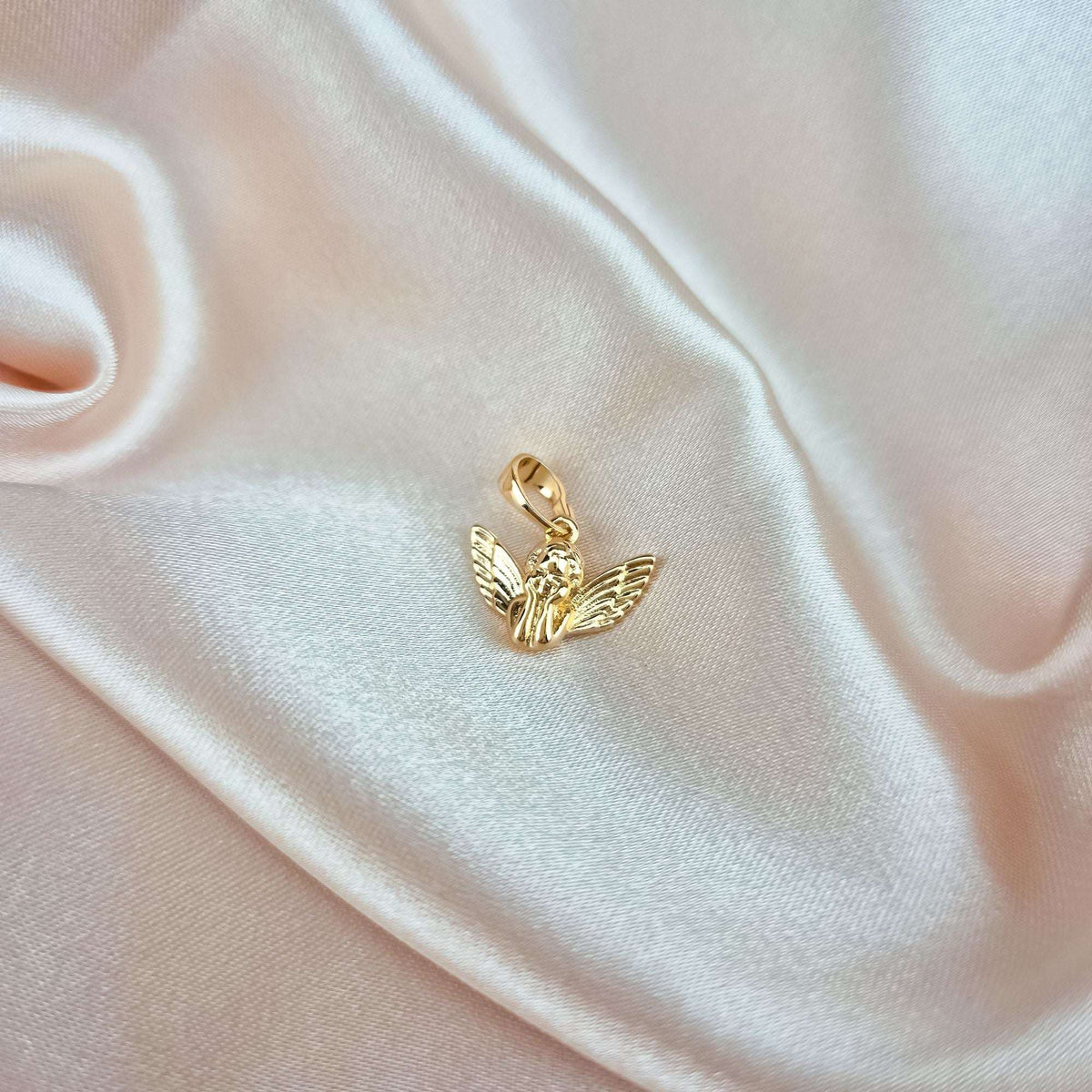 Small gold-plated angel pendant on cream silk showing its true size