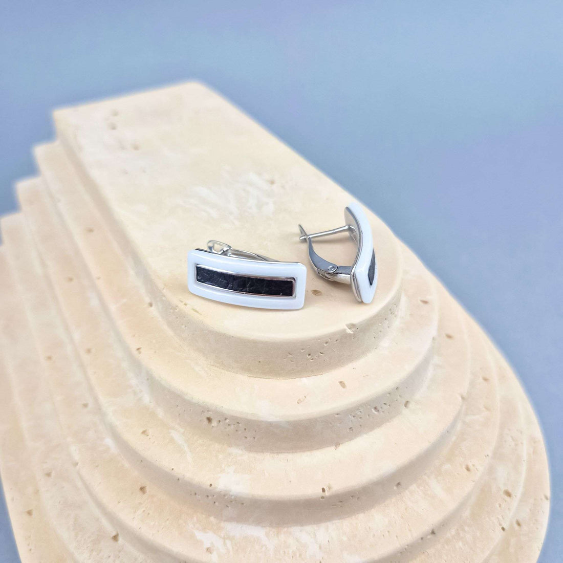 Side view of earrings with a white frame and black ceramic, leverback clasp visible