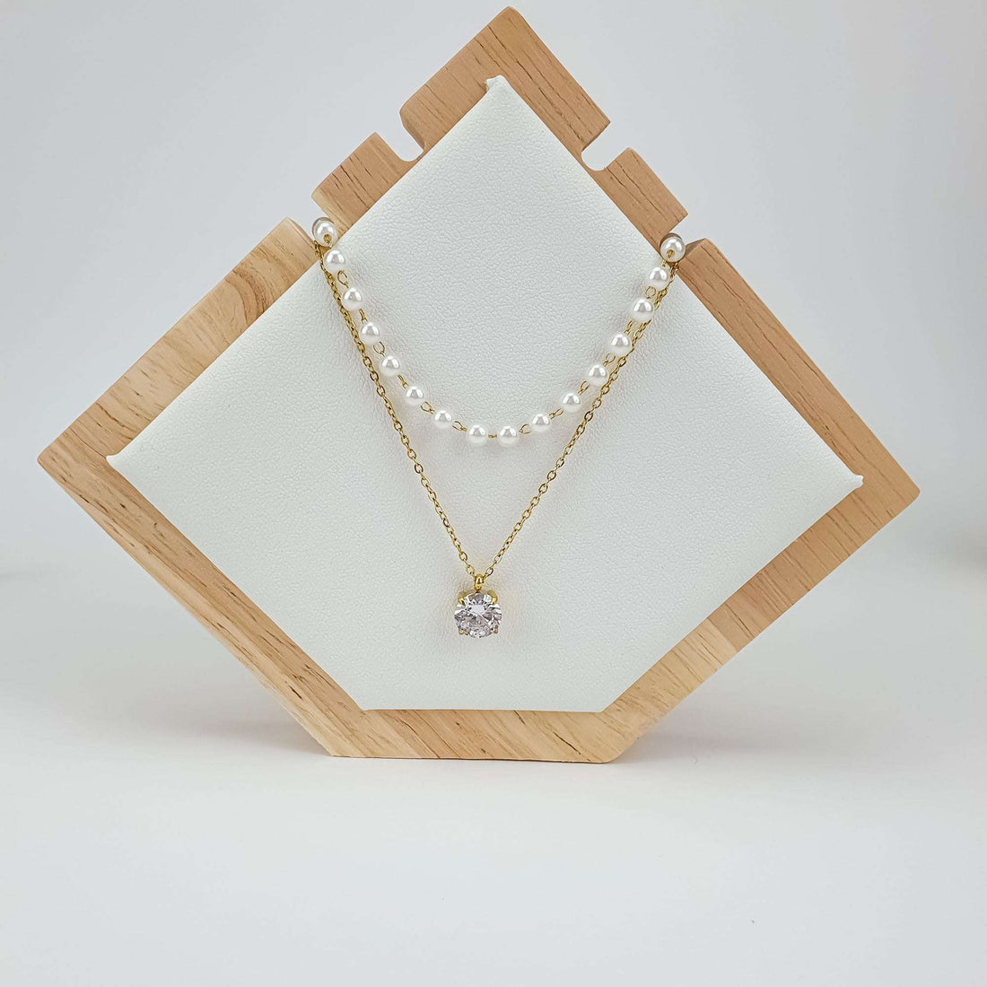 Layered necklace with pearls and a sparkling crystal on a wooden jewellery stand