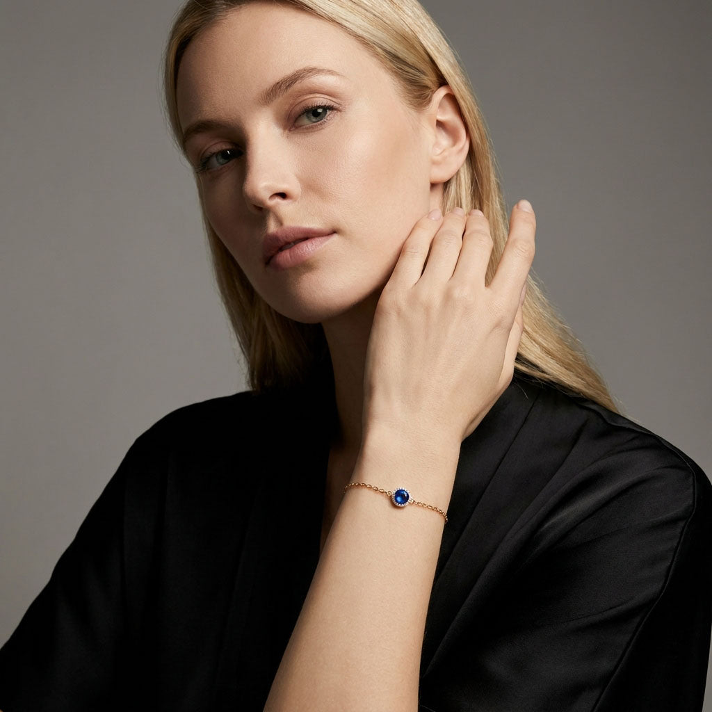 Model in a black silk outfit wearing a gold-tone bracelet with blue crystal