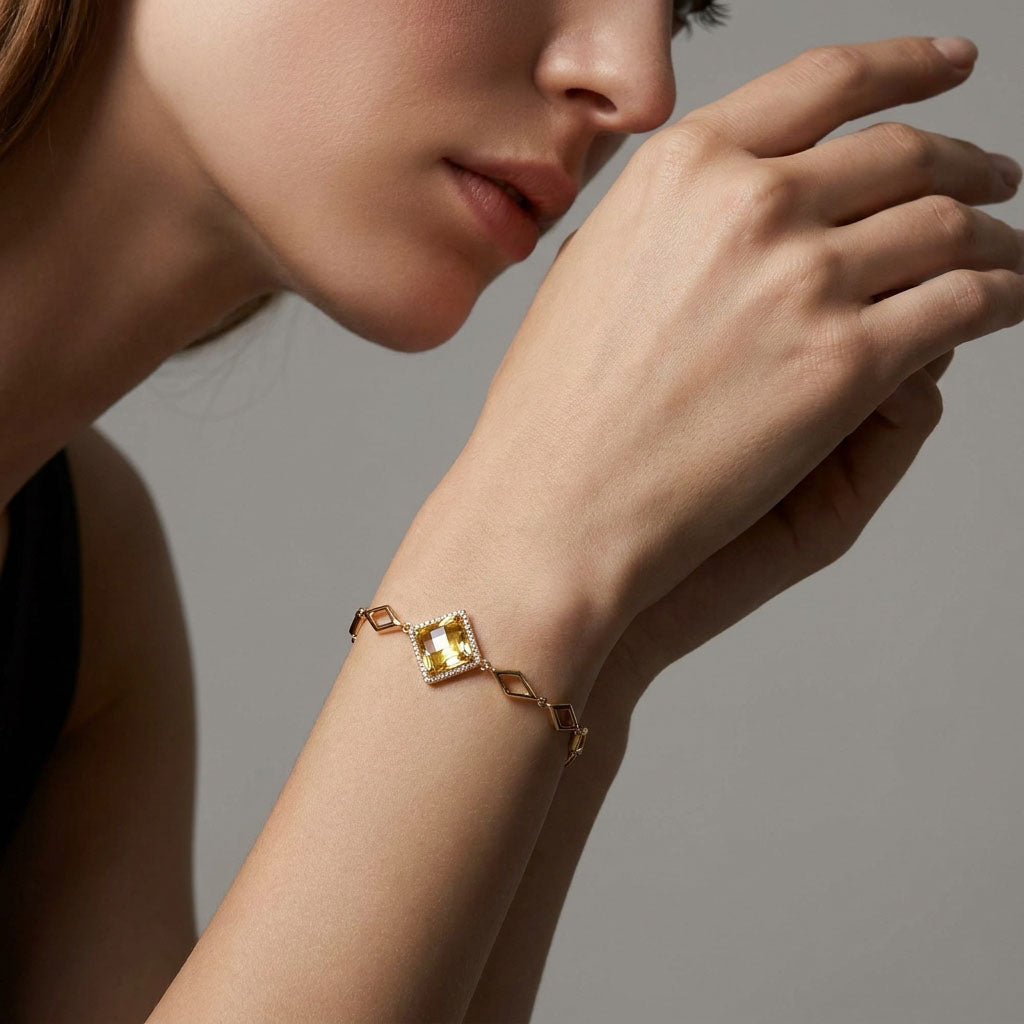 Gold-plated bracelet with a champagne crystal on a model's wrist, grey background