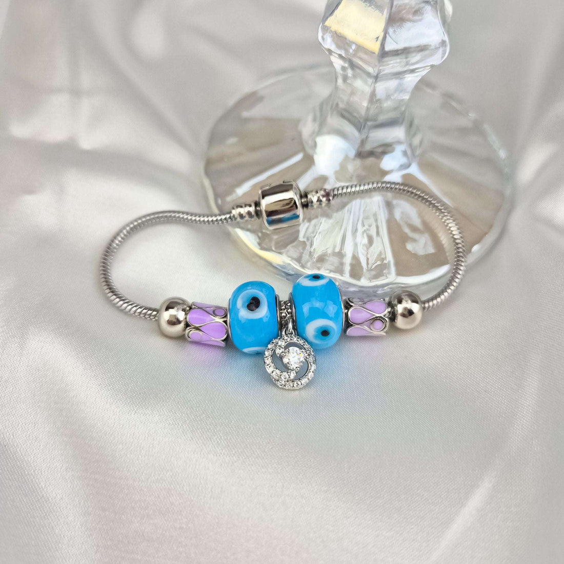 Close-up of the bead bracelet on pale silk, blue and pink enamel beads