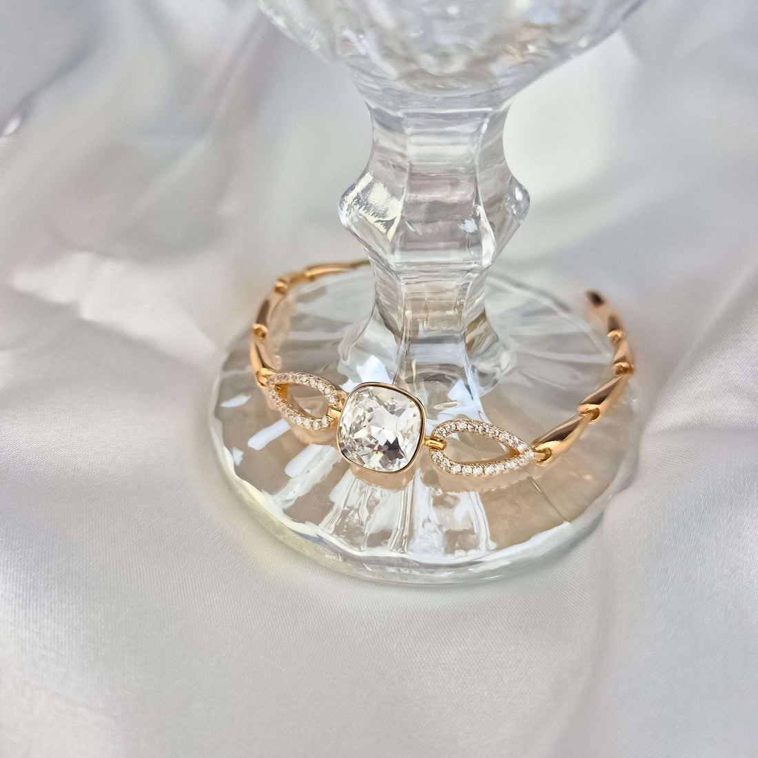 Bracelet with a sparkling crystal on a glass stand, cubic zirconia links visible