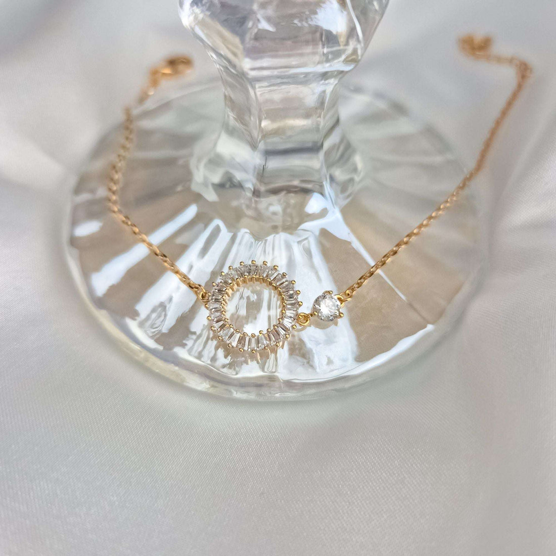 Close-up of a minimalist bracelet with a sparkling circle on glass and silk