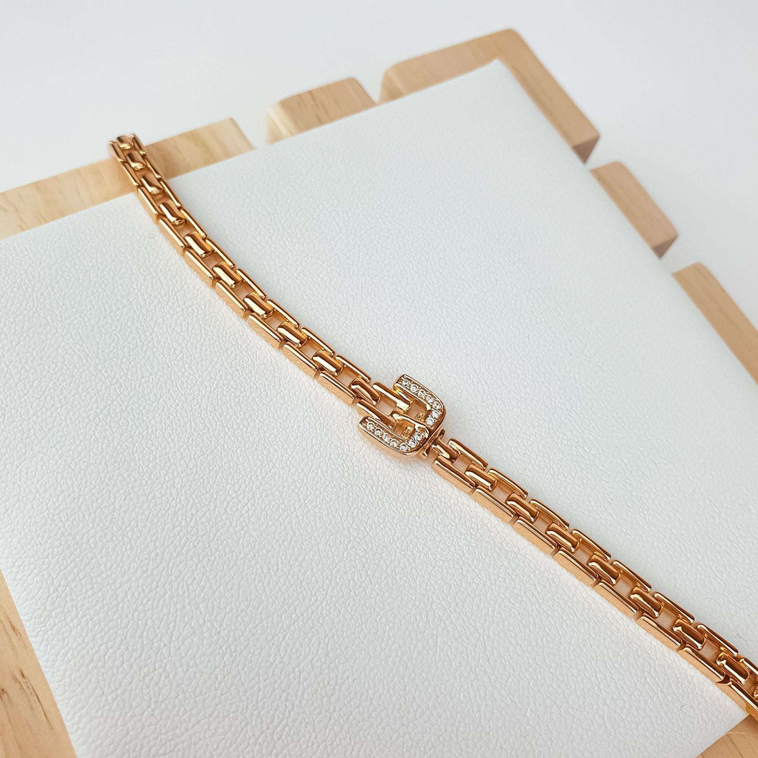 Bracelet with cubic zirconia buckle on white textured display with wooden edges