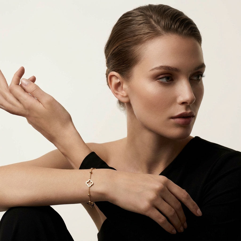 Model in a black blouse wearing the gold-tone clover bracelet on her wrist