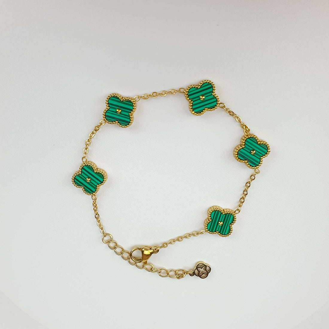 Green clover bracelet at an angle with gold plating, chain and extension charm