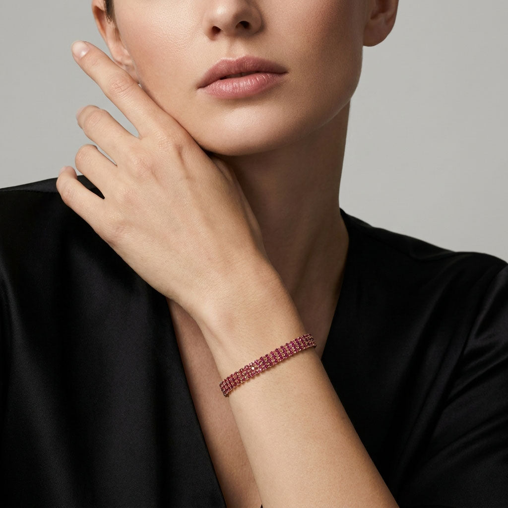 Pink three-row tennis bracelet on a model's wrist, gold-plated, evening look