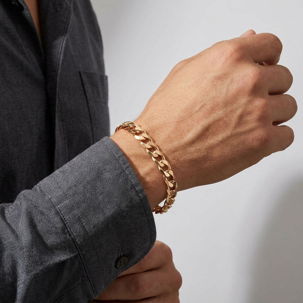 Gold-plated curb bracelet on a man's wrist beside a grey shirt cuff