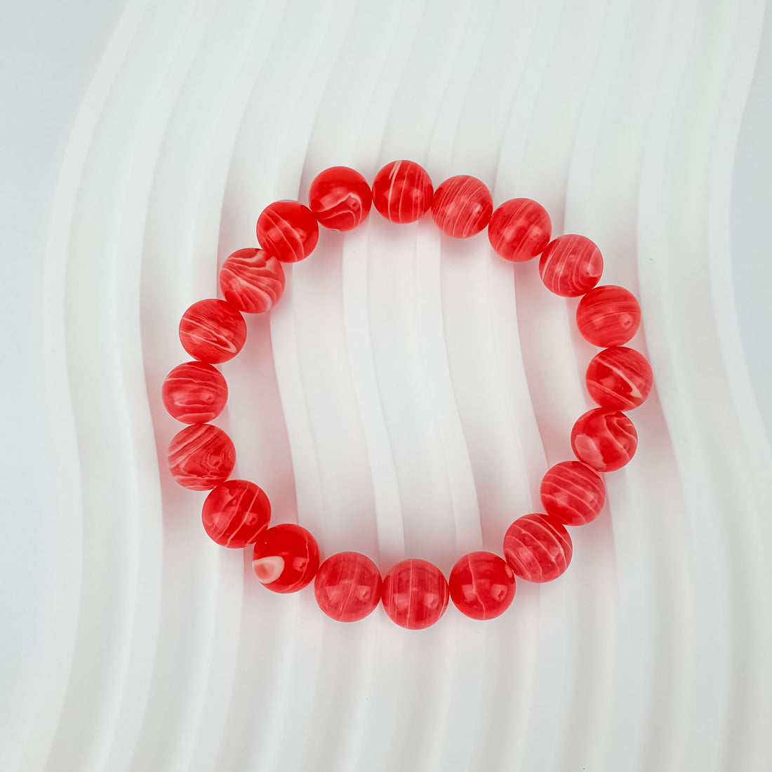 Stretch bracelet with red-pink imitation rhodochrosite beads, white banding in each stone