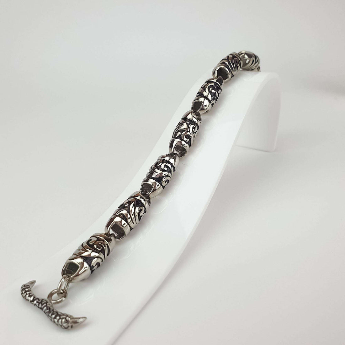 Bracelet close-up on a white stand, relief pattern and T-bar clasp visible