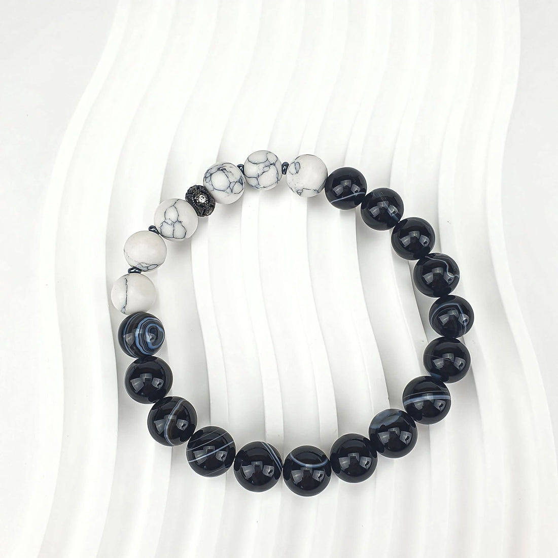 Bracelet on a wavy white background, glossy black and matt white beads