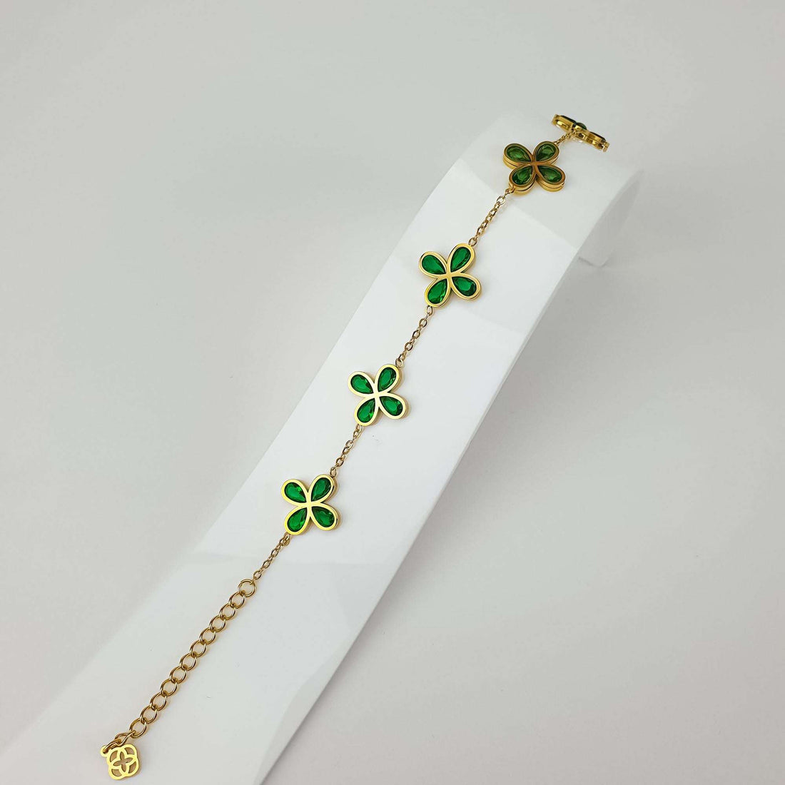 Clover bracelet with green crystals on a stand, showing the chain and extender