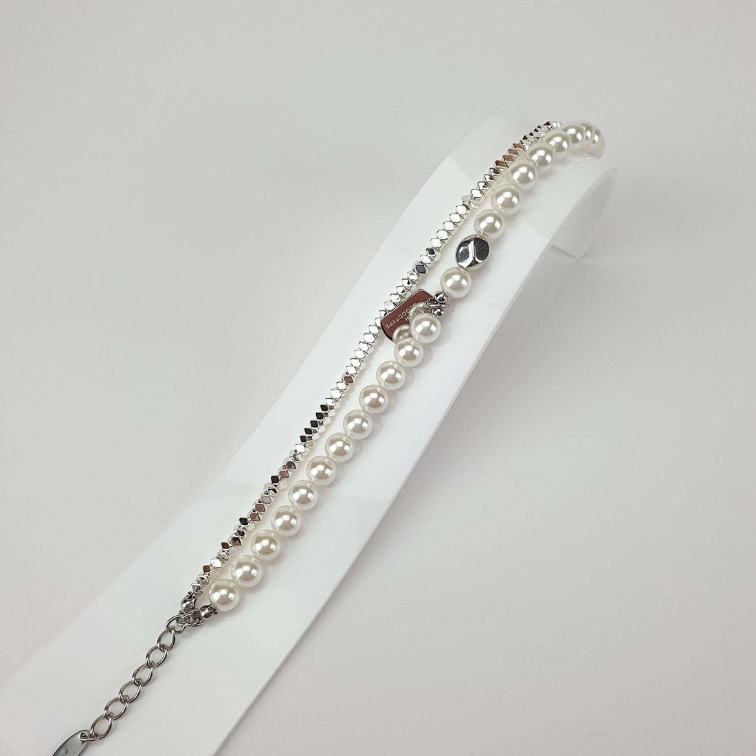 Faux pearl bracelet on a white stand with engraved tag and extension chain