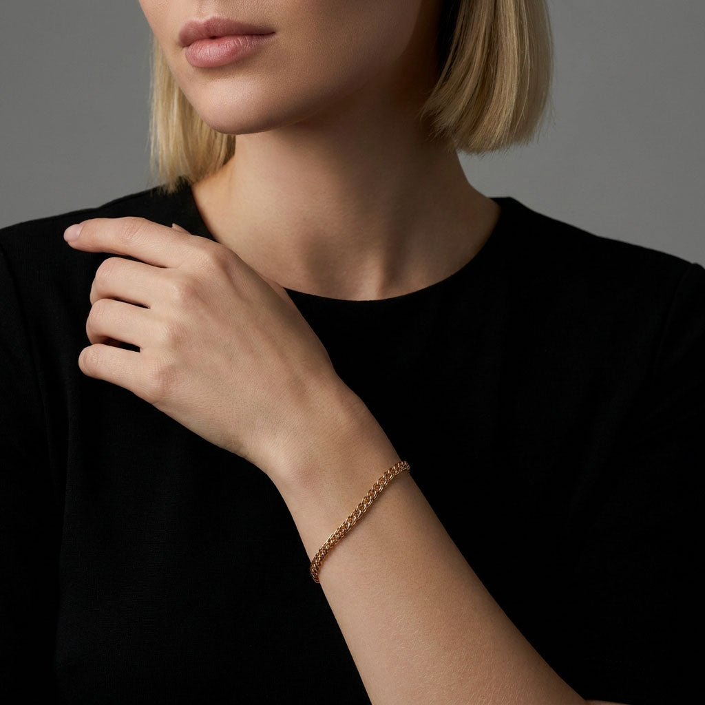 Rose gold-tone woven bracelet on a model's wrist, black outfit, grey background