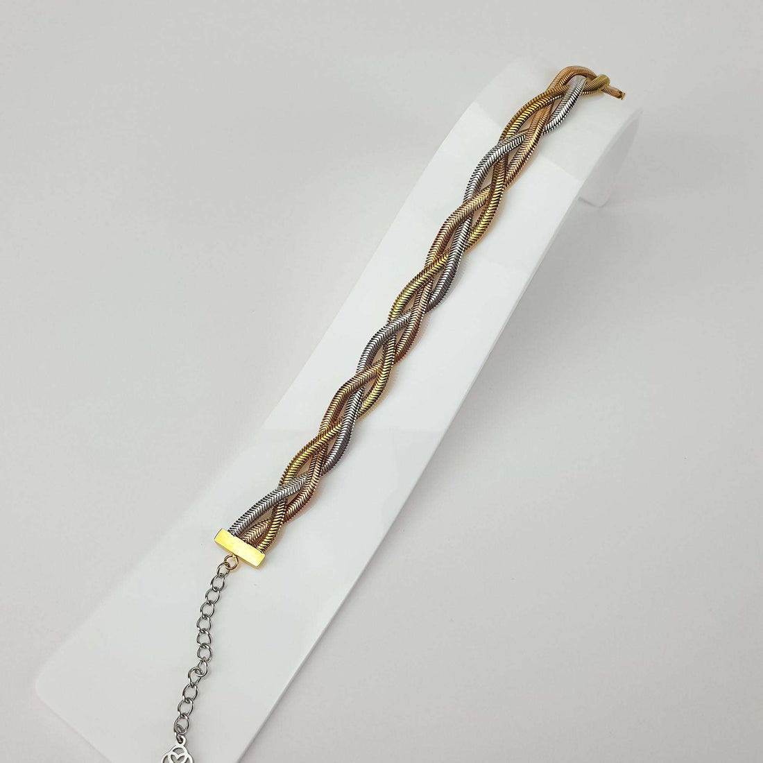 Three-tone braided bracelet at an angle on a white stand, showing the weave