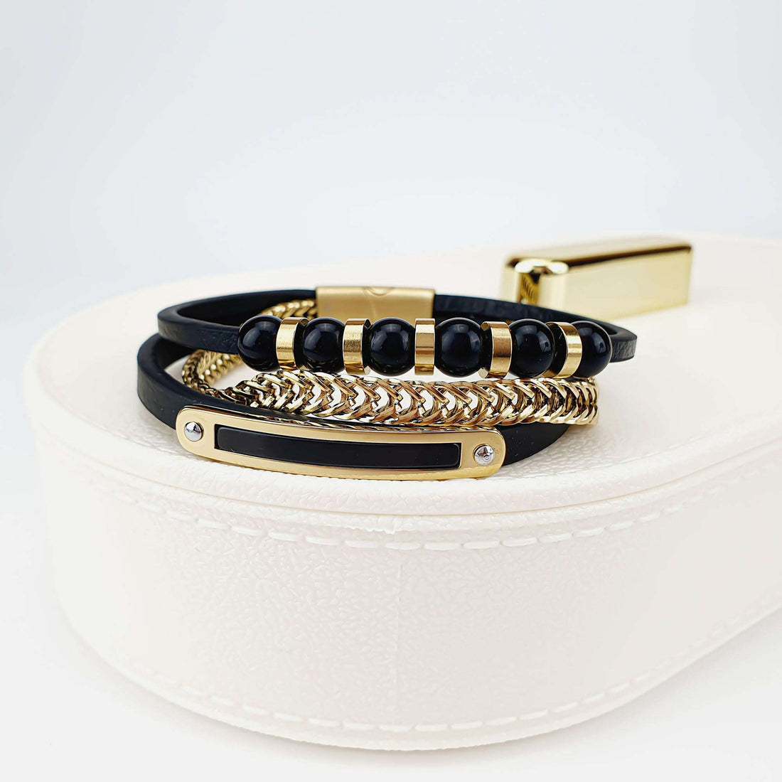 Black leather men's bracelet with a gold-tone plate on a white jewellery box